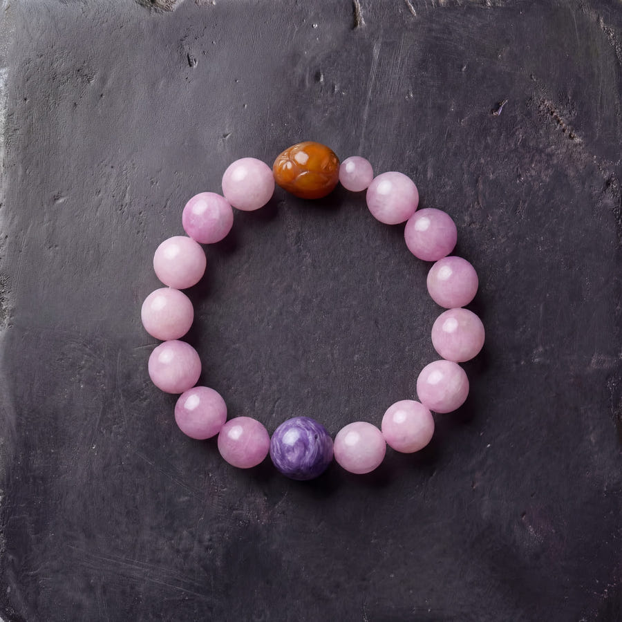 Z04 Violet Static bracelet — pink kunzite beads with charoite and one golden quartz bead, flat lay on dark stone