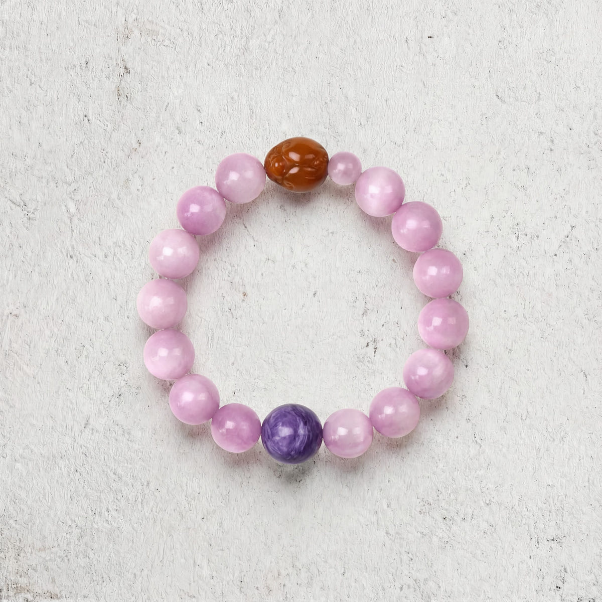 Z04 Violet Static bracelet top-down on light gray — soft pink kunzite with a purple charoite bead