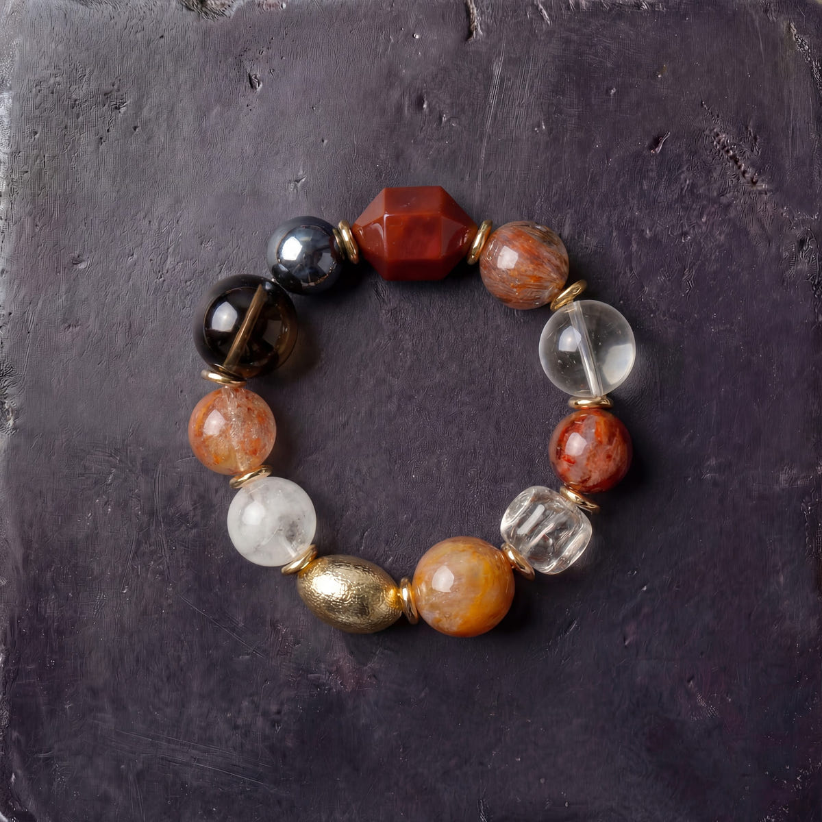Z06 Omni Matrix bracelet — smoky and hematoid quartz with a man-made terahertz bead and gold-tone accents, flat lay on dark stone